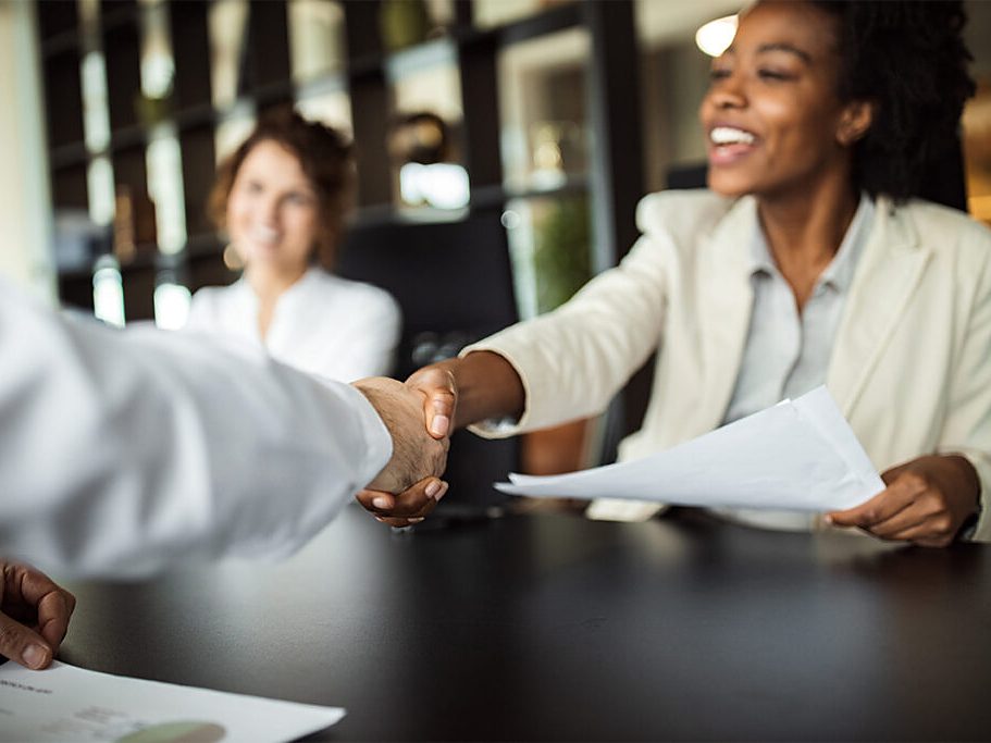 A businesswoman shakes hands across a conference table
