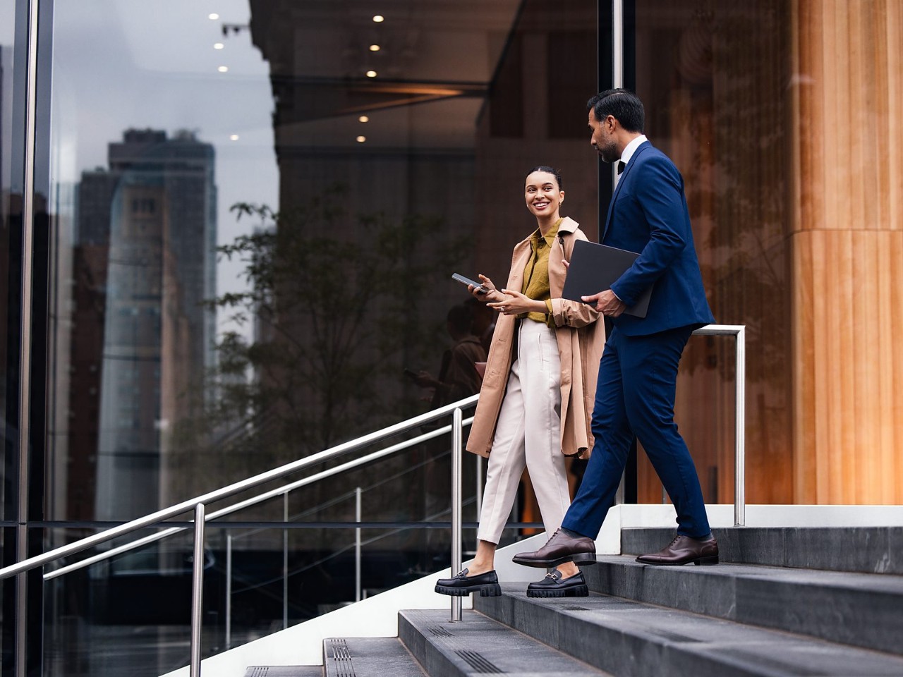 Two professionals talk as they walk down the steps of an office building