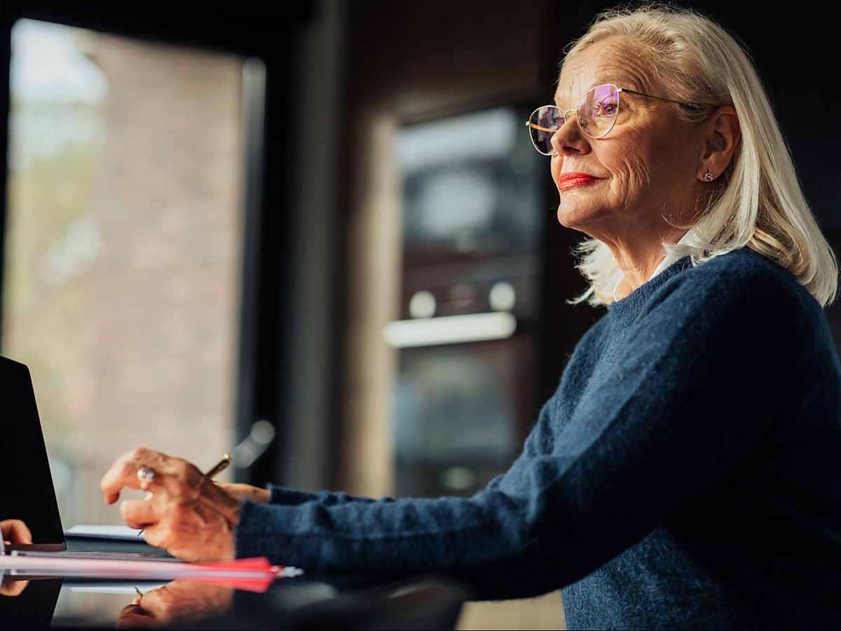A woman works at a laptop by a window