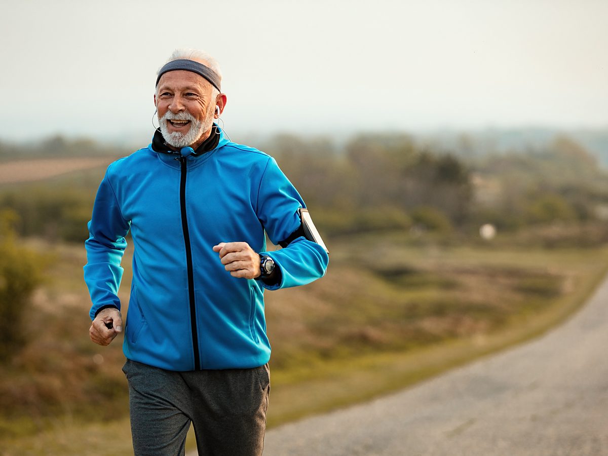 A man in a blue jacket runs along a quiet country road