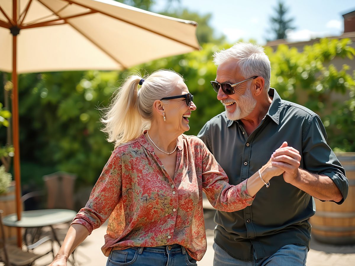 An older couple dances together on a sunny patio