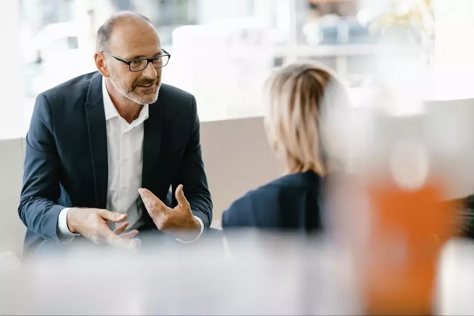 A financial advisor in glasses talking with a client