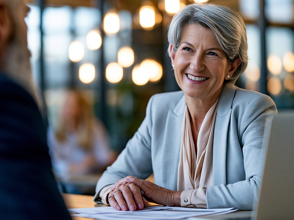 A smiling advisor at her desk meets with a client